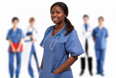 Portrait of a smiling nurse in front of a group of doctors