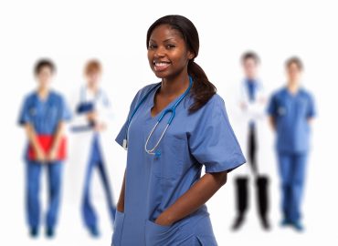 Portrait of a smiling nurse in front of a group of doctors